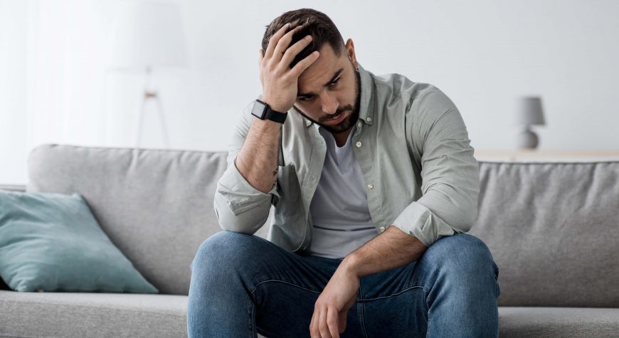 Man sitting with hand on his head thinking about the difference between mood disorder vs personality disorder.
