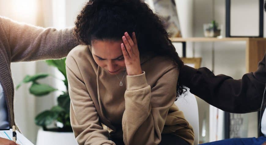 Distressed woman wondering what is a common physical reaction to trauma.
